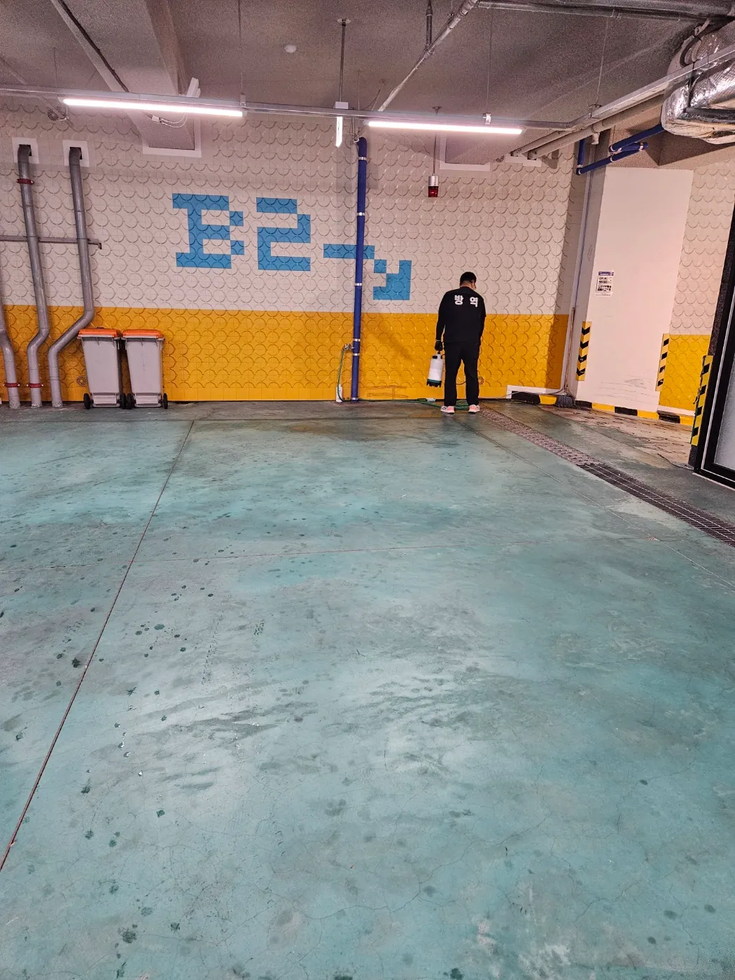 지하주차장 벽과 바닥 모서리를 방역하는 작업자
